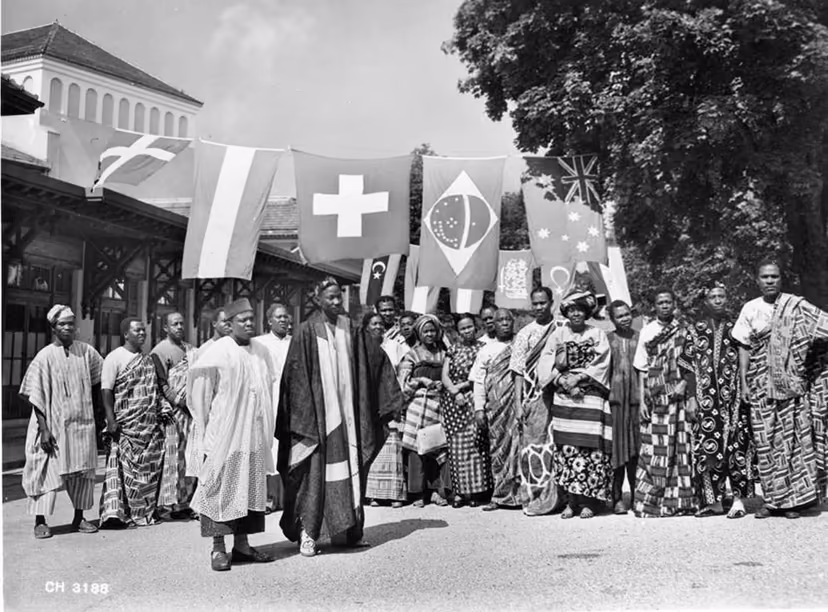 A delegation in traditional dress, photographed beneath a row of international flags